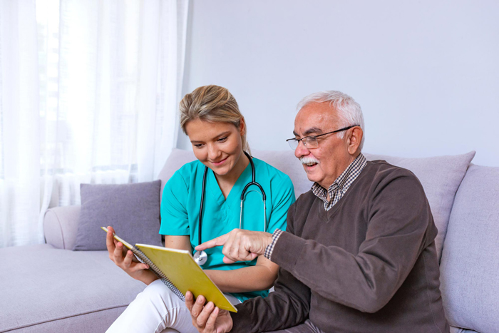 Man sitting on a couch, looking at a photo album and sharing fond memories with a tender caregiver