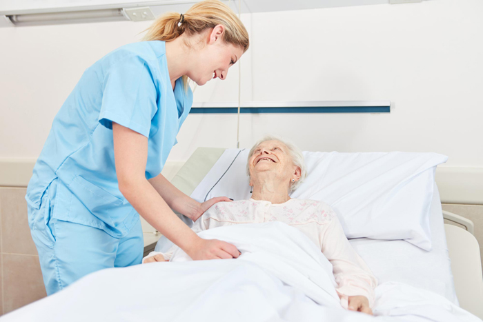 home care Nurse cares for a sick senior citizen in bed in nursing home or hospice